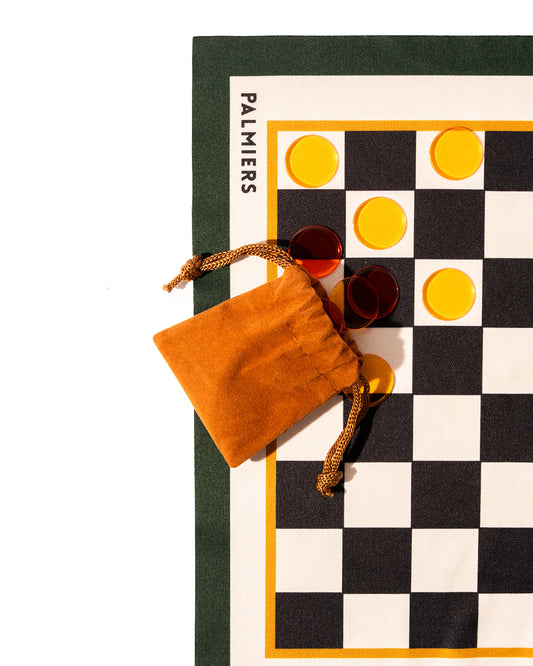 Checker board cloth with checker pieces using colors of orange, yellow, green,black and ivory.
